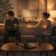 Two partners sit apart on a sofa, struggling with emotional closeness while a fragile connection stretches between them.