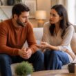 A couple sits together in a living room, sharing a calm and supportive conversation.